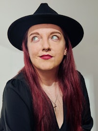 a woman with red hair wearing a black hat